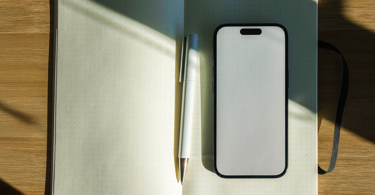 A minimalistic sunlit workspace featuring an open notebook, pen, and smartphone on a wooden desk.